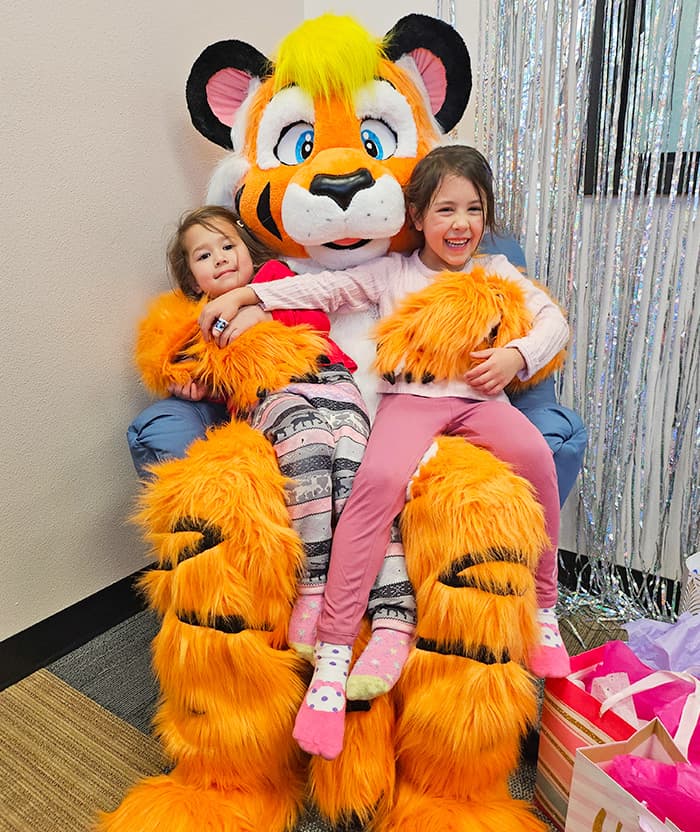Kids sitting on tiger mascot